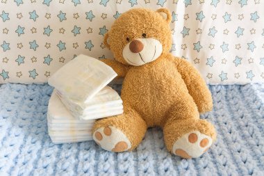 Bebek bezleri, bebek odası ve beşiğinin arka planında oyuncak ayı, bebek bezi kullanma kavramı.