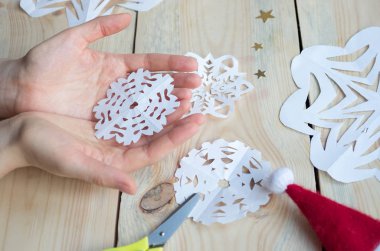 Kız, kağıttan yapılmış ev yapımı kar taneleri yapıyor. Yeni yıla hazırlanıyor. Noel, ev dekorasyonu.