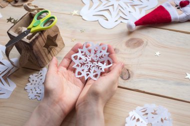 Kız, kağıttan yapılmış ev yapımı kar taneleri yapıyor. Yeni yıla hazırlanıyor. Noel, ev dekorasyonu.