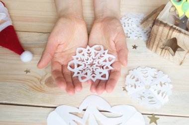 Kız, kağıttan yapılmış ev yapımı kar taneleri yapıyor. Yeni yıla hazırlanıyor. Noel, ev dekorasyonu.