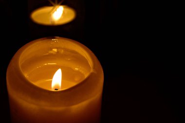 Siyah arka planda yanan mumların alevi makroyu kapatır.