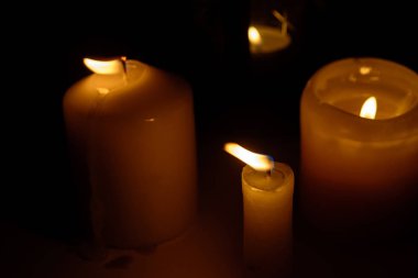 Siyah arka planda yanan mumların alevi makroyu kapatır.