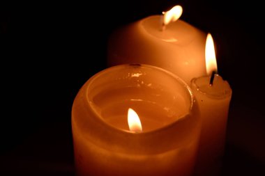 Siyah arka planda yanan mumların alevi makroyu kapatır.