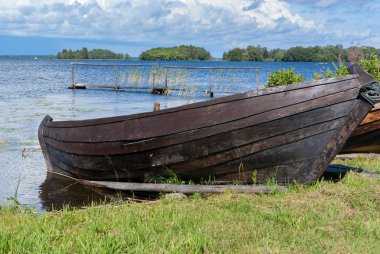 old wooden boat on oars on the shore of a blue cold lake
