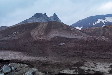 Volkanik vadi, volkanik böbrek ve kum, volkanın eteği, sis, bulutlar.