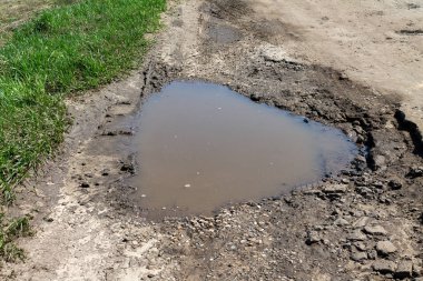 su dolu yolda büyük çukur, kötü kırık yollar kavramı, bakım ve yol yüzeyinin onarımı