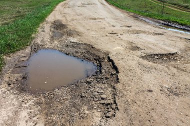 su dolu yolda büyük çukur, kötü kırık yollar kavramı, bakım ve yol yüzeyinin onarımı