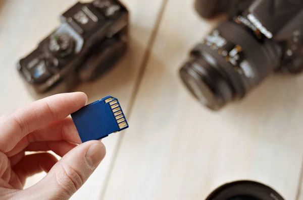 flash card in hand on camera background, memory card for SLR camera, flash drive, photo storage, toned