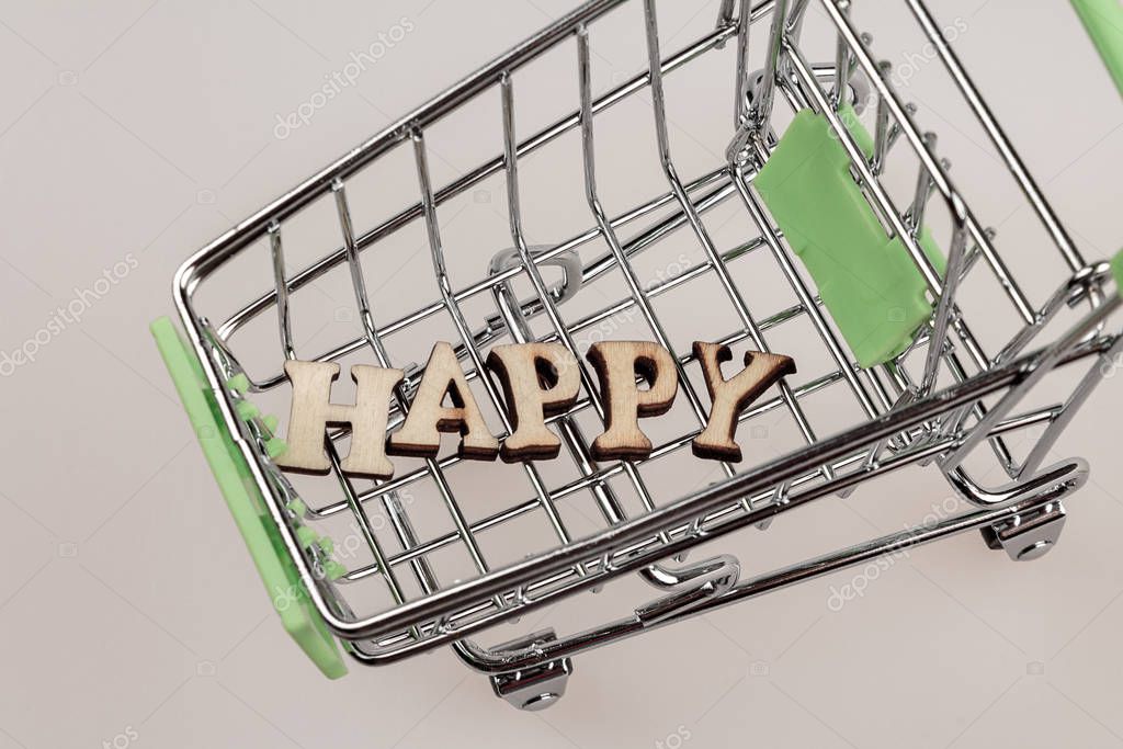 Shopping cart with the inscription happiness lined with letters, the concept of a happy person, money can not buy happiness