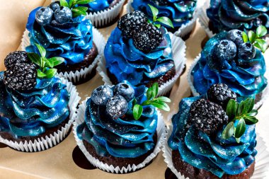 Mavi kremalı, yaban mersinli, böğürtlenli, el yapımı tatlılı, yakın çekim manzaralı bir dizi güzel ağız sulandırıcı kek.