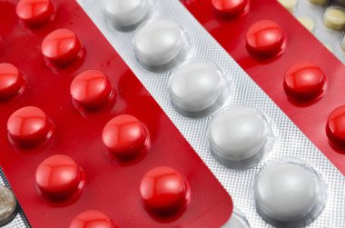 Yuvarlak renkli tabletlerle su toplayan kabarcıklar kırmızı beyaz, açık arka plan makro, antibiyotikler, vitaminler, ağrı kesici, antihistaminler, antialerjik maddeler.