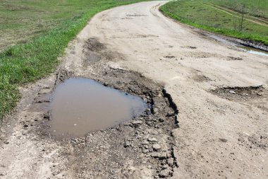 su dolu yolda büyük çukur, kötü kırık yollar kavramı, bakım ve yol yüzeyinin onarımı