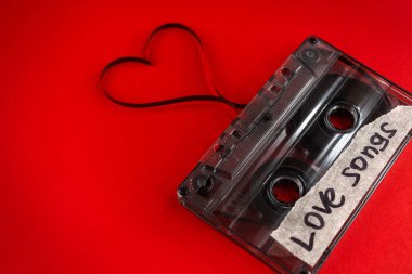 vintage old film music cassette on a trendy pink red background with the inscription love song, background music, music lovers, heart