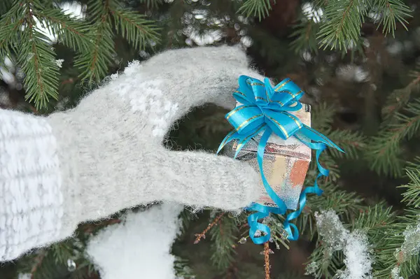 Рука Женщины Шерстяной Варежке Держит Упакованную Подарочную Коробку Зимой Заснеженной — стоковое фото