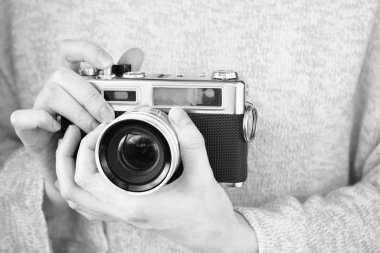 Elinde fotoğraf makinesi olan bir kız siyah beyaz fotoğraf çekiyor.