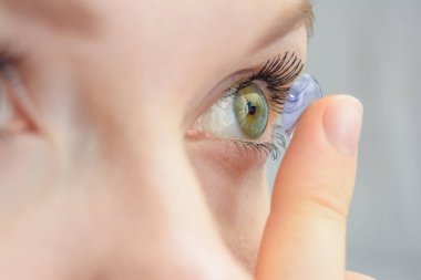Kız parmağını tutar ve bir günlük ya da planlı değişiklik için yumuşak bir lens takar. Miyopya sorunu, kötü görme, göz bakımı, modern silikon lens takması.