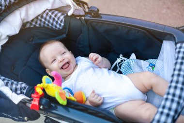 Anne ve babasıyla bebek arabasında yürüyüşe çıkmış küçük bir çocuk.