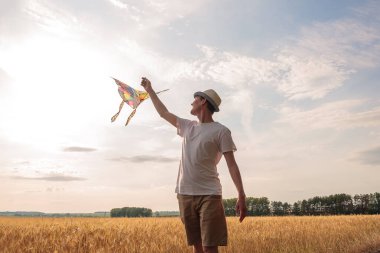Yazın mavi gökyüzüne karşı uçurtma uçurmak, uçurtma fırlatmak, eğlenceli yaz tatili, sahanın altında, serbest konsept