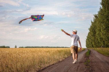 Yazın mavi gökyüzüne karşı uçurtma uçurmak, uçurtma fırlatmak, eğlenceli yaz tatili, sahanın altında, serbest konsept