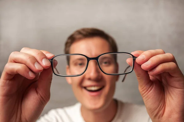 Joven Sostiene Gafas Con Lentes Dioptrías Las Mira Través Ellas — Foto de Stock