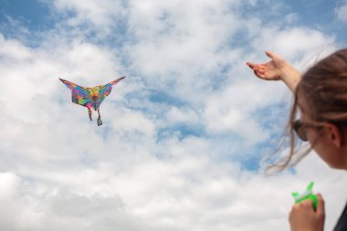 Yazın mavi gökyüzüne karşı uçurtma uçurmak, uçurtma fırlatmak, eğlenceli yaz tatili, sahanın altında, serbest konsept