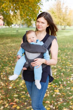 Küçük bebek askılı ergorace bir annede oturuyor, çocuğu sırtında yük olmadan dik bir pozisyonda taşıyor.