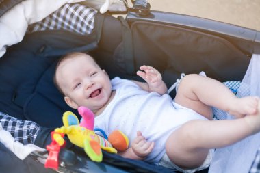 Anne ve babasıyla bebek arabasında yürüyüşe çıkmış küçük bir çocuk.