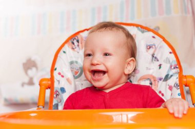 Küçük bir çocuk kaşıkla yer ve çocuk odasındaki beslenme masasının kenarına oturur, kirlidir ve besin, bebek maması konsepti, tamamlayıcı gıdalar, ilk kaşık