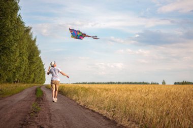 Yazın mavi gökyüzüne karşı uçurtma uçurmak, uçurtma fırlatmak, eğlenceli yaz tatili, sahanın altında, serbest konsept