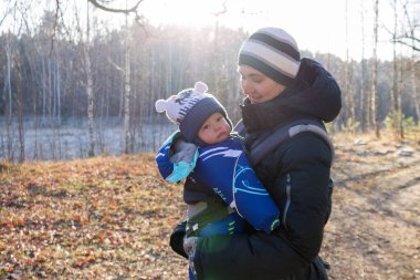 Küçük bebek askının üzerinde oturur, ergorace baba, çocuğu dik bir pozisyonda taşır omurgasında yük olmadan