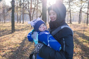 Küçük bebek askının üzerinde oturur, ergorace baba, çocuğu dik bir pozisyonda taşır omurgasında yük olmadan