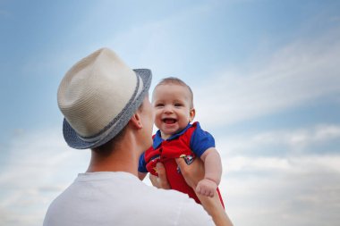 Küçük bebek babasının kollarında mavi gökyüzüne karşı, Babalar Günü, babalık, mutlu bebek