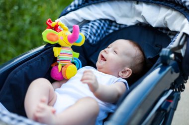 Anne ve babasıyla bebek arabasında yürüyüşe çıkmış küçük bir çocuk.