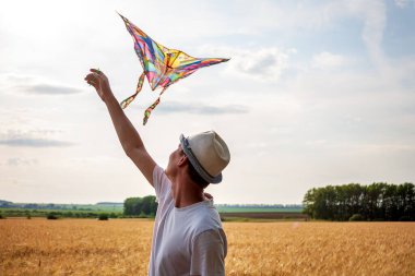 Yazın mavi gökyüzüne karşı uçurtma uçurmak, uçurtma fırlatmak, eğlenceli yaz tatili, sahanın altında, serbest konsept
