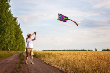 Yazın mavi gökyüzüne karşı uçurtma uçurmak, uçurtma fırlatmak, eğlenceli yaz tatili, sahanın altında, serbest konsept