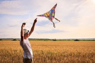 Yazın mavi gökyüzüne karşı uçurtma uçurmak, uçurtma fırlatmak, eğlenceli yaz tatili, sahanın altında, serbest konsept