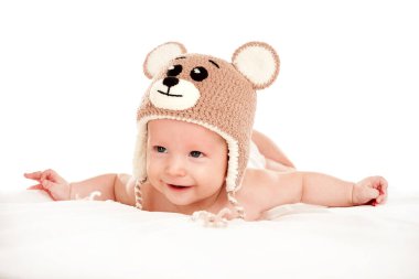 Bebek yeni doğmuş bebek, beyaz arka planda izole edilmiş komik örgü bir şapkayla yatar. Bebek kıyafetleri, yıkama ve bakım konsepti.