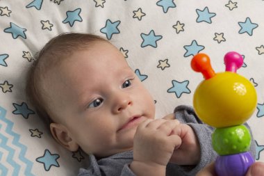 Küçük mutlu çocuk sallanan çıngıraklarla oynuyor, yeni doğan bebekler için oyuncaklar, ilk oyuncak