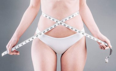 Beyaz bikinili kız belini ölçüyor.