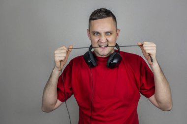 Kırmızı tişörtlü genç adam kulaklıklarıyla dantel yırtıyor.