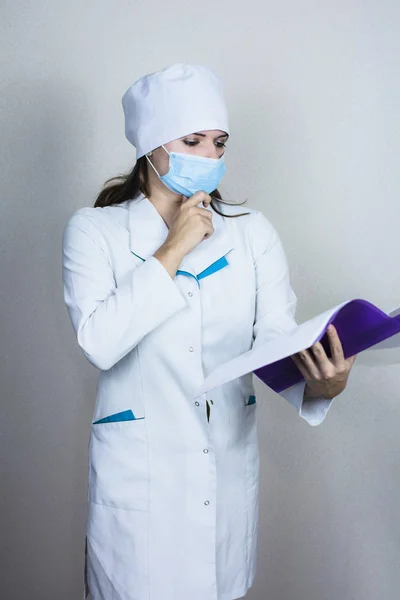 Врач Женщина Медицинской Маске Ищет Бумагу Белом Фоне — стоковое фото