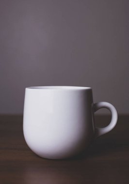 Gri arkaplanlı tahta masanın üzerinde beyaz fincan 