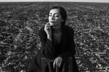  Saçları rüzgarda uçuşan siyah paltolu kadın duruyor. 