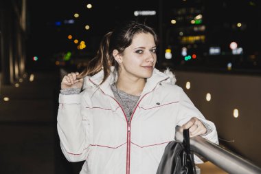 Bir gece şehrinin sokaklarında siyah saçlı genç bir kızın portresi.