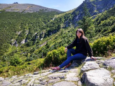 Genç neşeli yürüyüşçü kız koyu saçlı yüksek dağlarda yaz mevsiminde.