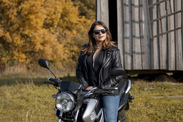 Deri ceketli, gözlüklü motosikletli genç bir kız.