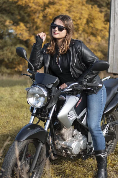穿着皮夹克和眼镜坐在摩托车上的年轻姑娘 — 图库照片