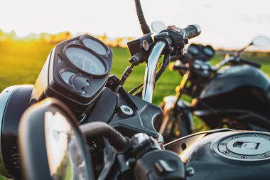 Sıcak renklerde günbatımının arka planında iki siyah motosiklet.