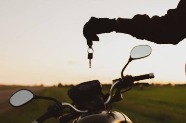 Motosikletlerin arka planında siyah bir ulaşım anahtarı tutan adam.