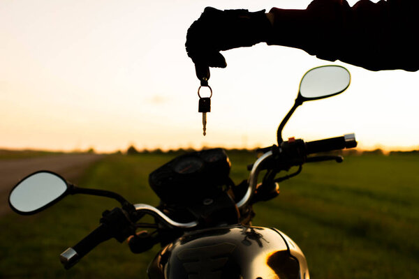 man holding a dark transport key on a background of motorcycles